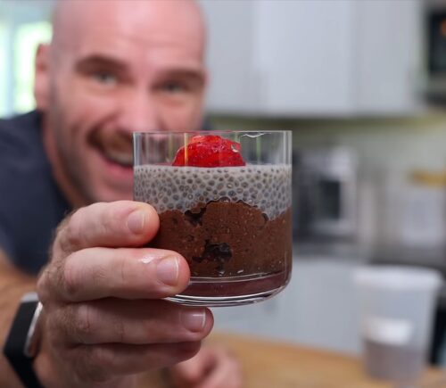 Mark Thompson stands in his kitchen holding a glass dessert cup of chia pudding in his video 'I Ate Chia Seeds Every Day for a Month.'