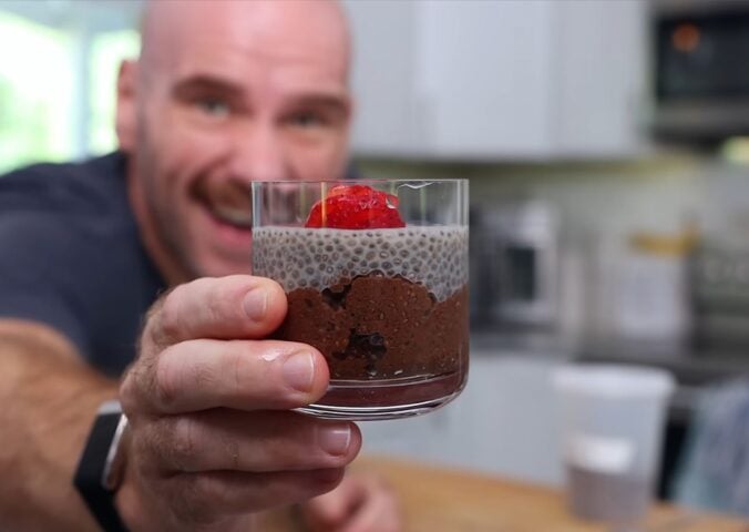 Mark Thompson stands in his kitchen holding a glass dessert cup of chia pudding in his video 'I Ate Chia Seeds Every Day for a Month.'