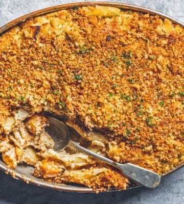 a dish of vegan baked ziti alfredo made with ziti pasta, vegan alfredo sauce, asparagus, mozzarella, and breadcrumbs