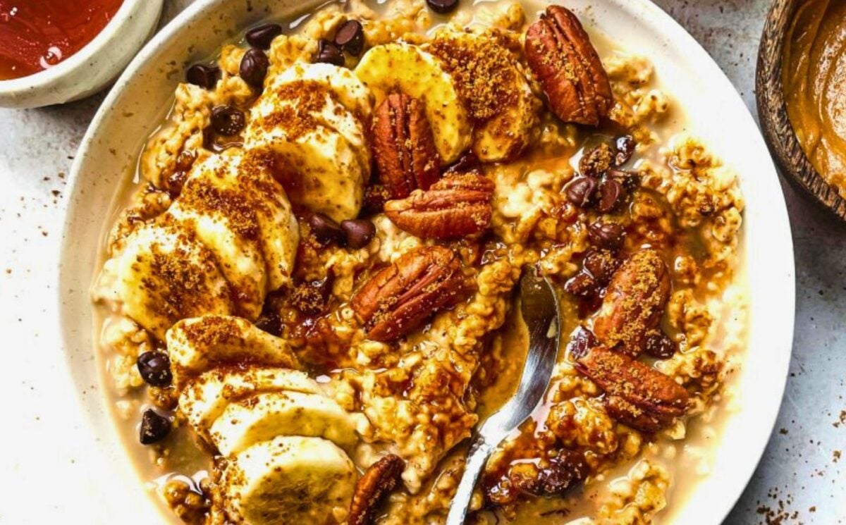 a bowl of banana, walnut and chocolate porridge with nutty drizzle and vegan protein powder