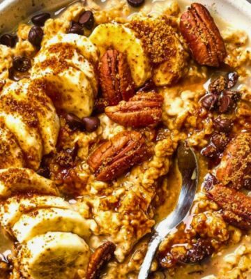 a bowl of banana, walnut and chocolate porridge with nutty drizzle and vegan protein powder