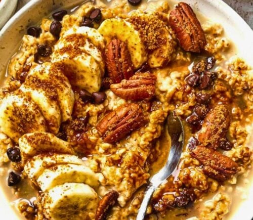 a bowl of banana, walnut and chocolate porridge with nutty drizzle and vegan protein powder