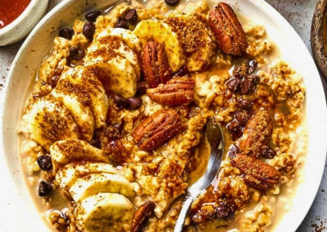 a bowl of banana, walnut and chocolate porridge with nutty drizzle and vegan protein powder