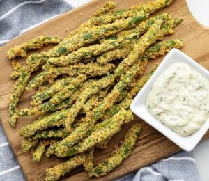 A wooden chopping board covered in oil-free green bean fries for green bean recipes