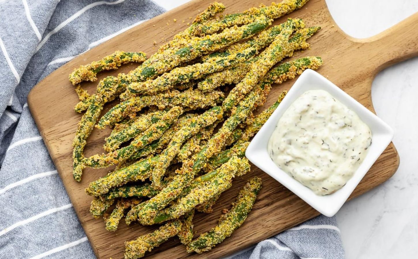 A wooden chopping board covered in oil-free green bean fries for green bean recipes