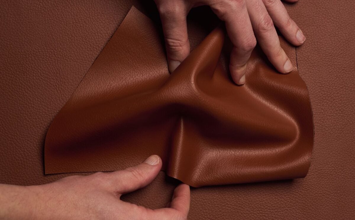 Photo shows someone's hands as they spread out a piece of "ELEVATE," a plant-based leather alternative for car interiors produced by UNCAGED and Hyundai