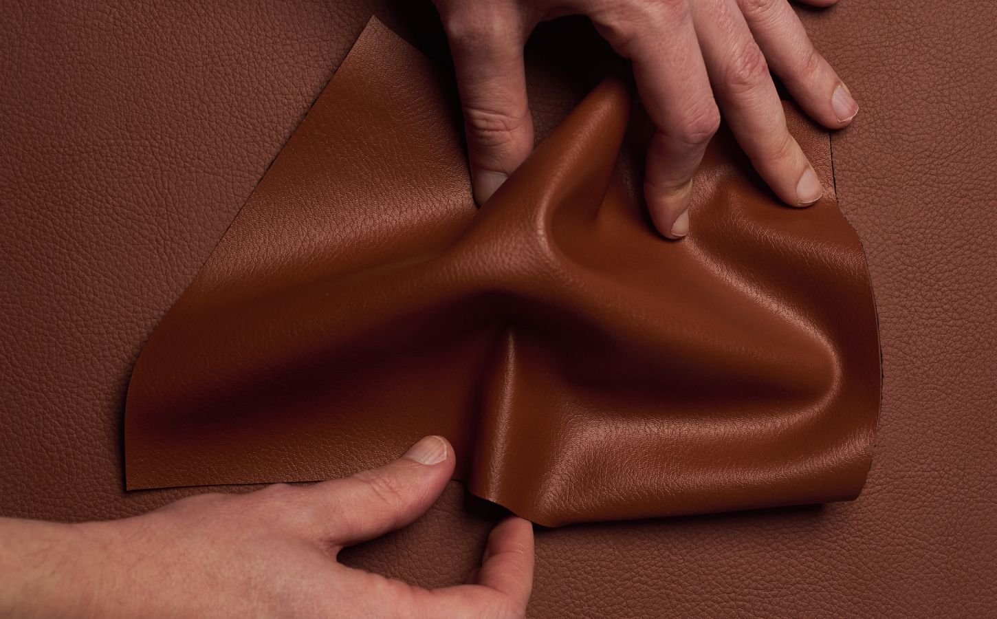 Photo shows someone's hands as they spread out a piece of "ELEVATE," a plant-based leather alternative for car interiors produced by UNCAGED and Hyundai