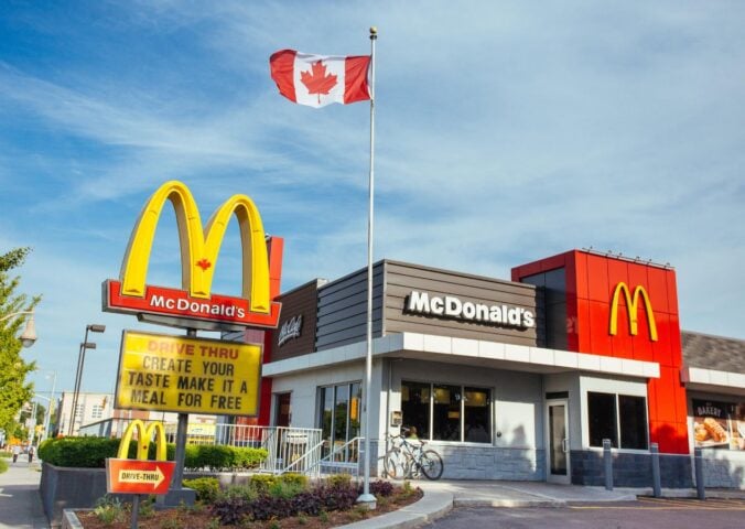 Photo shows a McDonald's restaurant in Canada with a Canadian flag flying above it