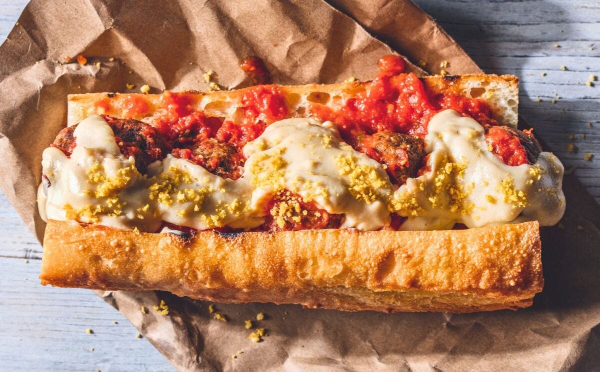 a vegan meatball parmigiana hero with cashew mozzarella, lentil meatballs, and basil