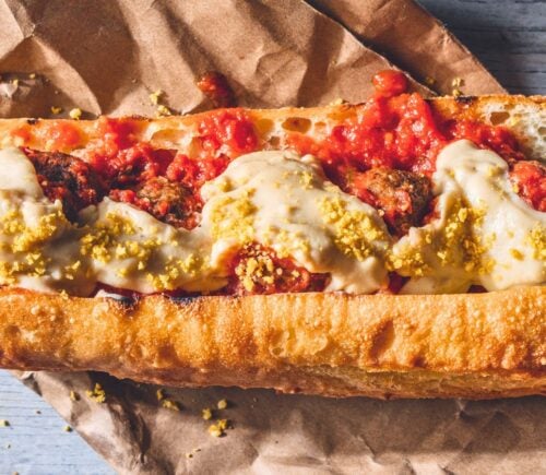 a vegan meatball parmigiana hero with cashew mozzarella, lentil meatballs, and basil