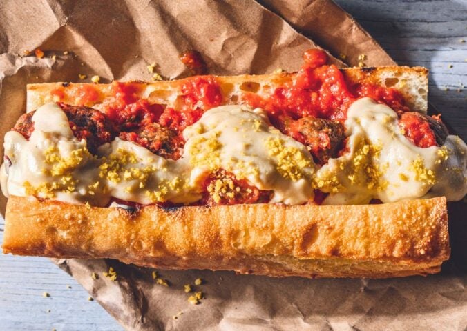 a vegan meatball parmigiana hero with cashew mozzarella, lentil meatballs, and basil