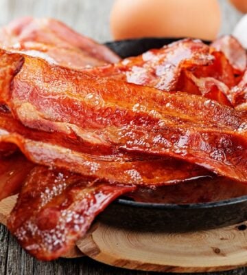 Photo shows a bowl of bacon next two whole eggs