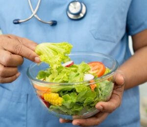 Plant-based diets are thought to cut disease risk, and the photo shows a Dr wearing scrubs and a stethoscope holding a glass bowl of salad