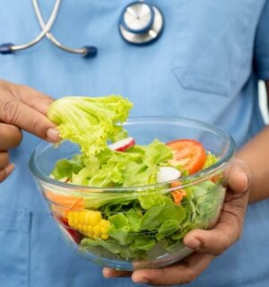 Plant-based diets are thought to cut disease risk, and the photo shows a Dr wearing scrubs and a stethoscope holding a glass bowl of salad