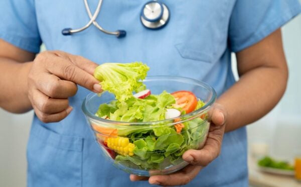 Plant-based diets are thought to cut disease risk, and the photo shows a Dr wearing scrubs and a stethoscope holding a glass bowl of salad