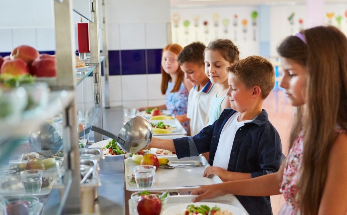 Nearly half of UK parents want more plant-based meals in schools. Photo shows a queue of school children loading their trays with fruit and vegetables