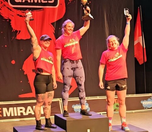 Photo shows vegan athlete Angeline Berva on the finishers' podium at the the European Strongman Games alongside her competitors
