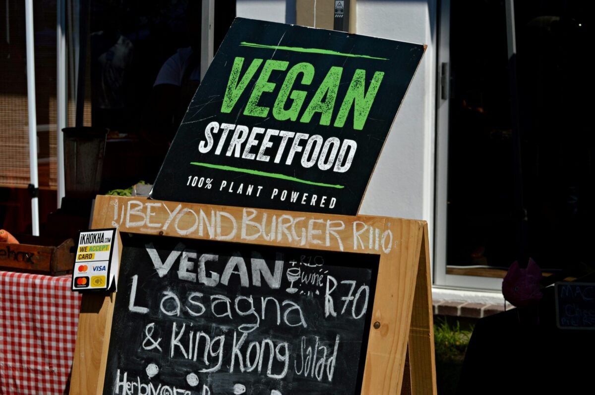 Photo shows a sign for vegan streetfood outside of a food truck