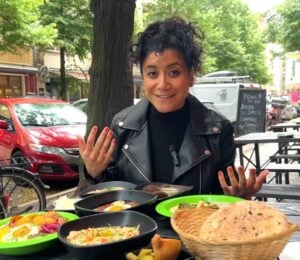 Eunice Reyes sitting at a table filled with hummus, falafel, and other Middle Eastern dishes at Dr. Hummus, showcasing vegan food in Berlin