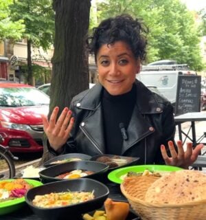 Eunice Reyes sitting at a table filled with hummus, falafel, and other Middle Eastern dishes at Dr. Hummus, showcasing vegan food in Berlin