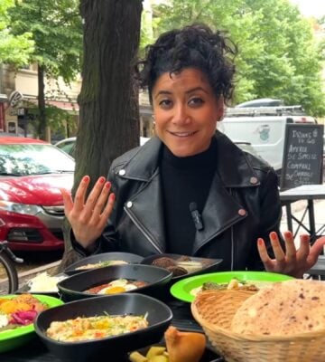 Eunice Reyes sitting at a table filled with hummus, falafel, and other Middle Eastern dishes at Dr. Hummus, showcasing vegan food in Berlin