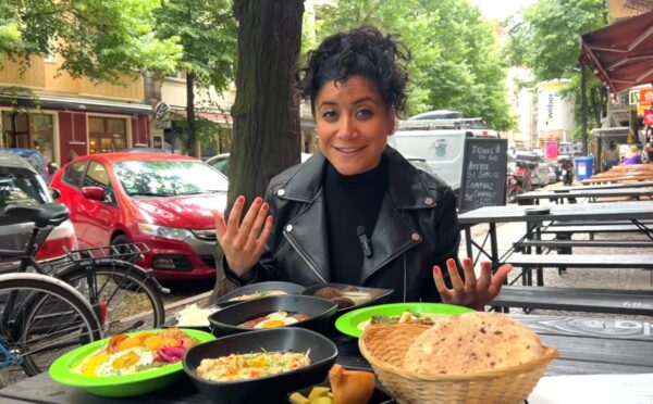 Eunice Reyes sitting at a table filled with hummus, falafel, and other Middle Eastern dishes at Dr. Hummus, showcasing vegan food in Berlin