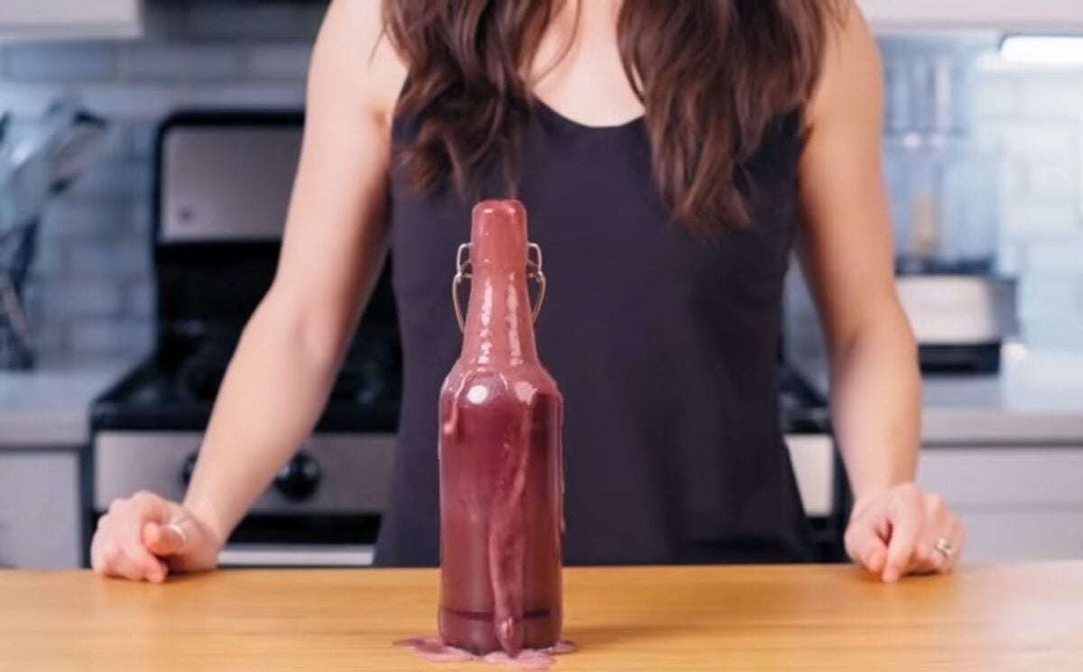 Cameron Rodas stands in her kitchen behind a bottle of her homemade probiotic soda