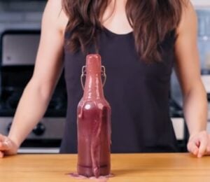 Cameron Rodas stands in her kitchen behind a bottle of her homemade probiotic soda