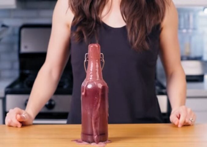 Cameron Rodas stands in her kitchen behind a bottle of her homemade probiotic soda