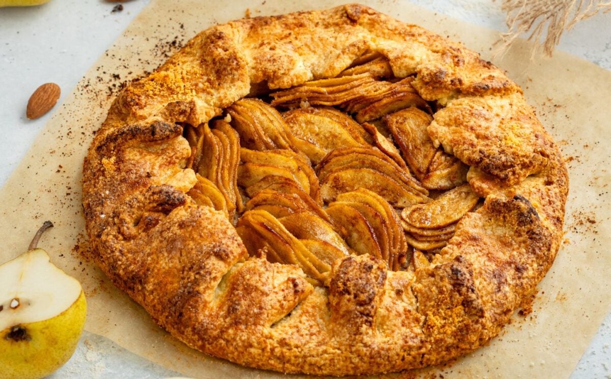 an image of an almond pear galette with slices of almond and pear surrounding the tart for cozy vegan bakes for afternoon tea