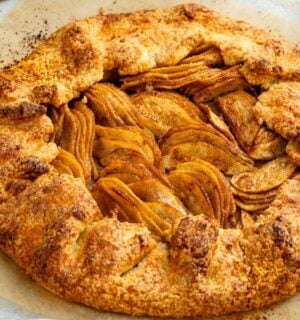 an image of an almond pear galette with slices of almond and pear surrounding the tart for cozy vegan bakes for afternoon tea