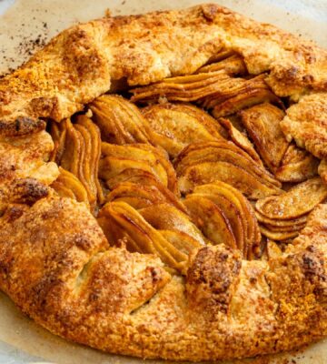 an image of an almond pear galette with slices of almond and pear surrounding the tart for cozy vegan bakes for afternoon tea
