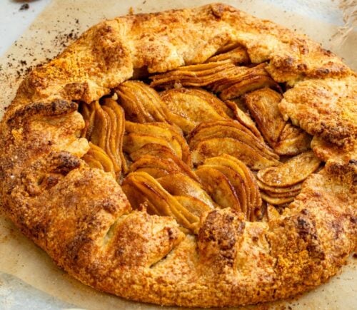 an image of an almond pear galette with slices of almond and pear surrounding the tart for cozy vegan bakes for afternoon tea