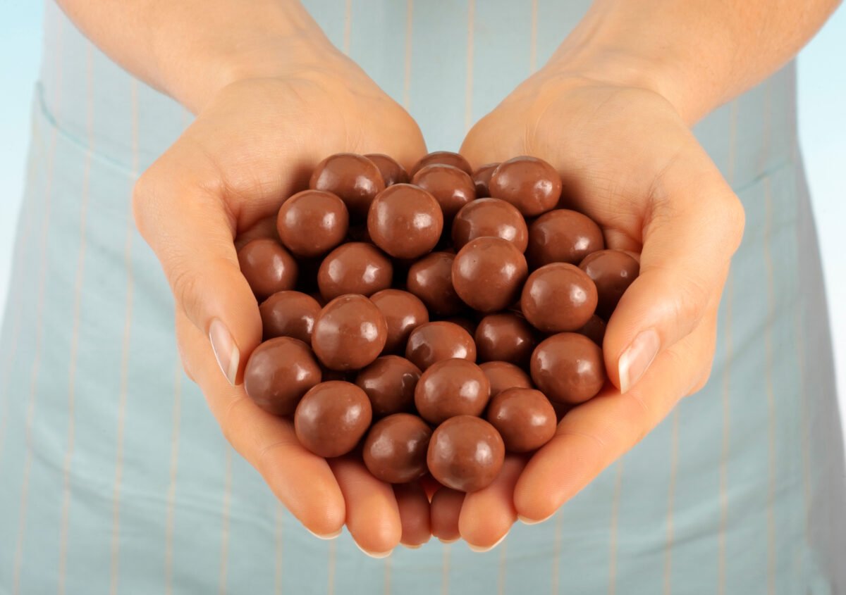 Photo shows someone holding a large handful of loose Maltesers