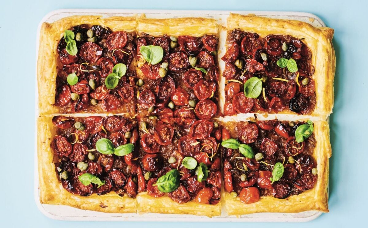 a picture of six squares of a caramelized shallot and tomato tart topped with basil and capers for vegan savory tart ideas