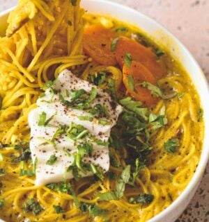 a bowl of vegan creamy coconut curry ramen with carrot, soft tofu, lime, and herbs for cozy lunch recipes for fall