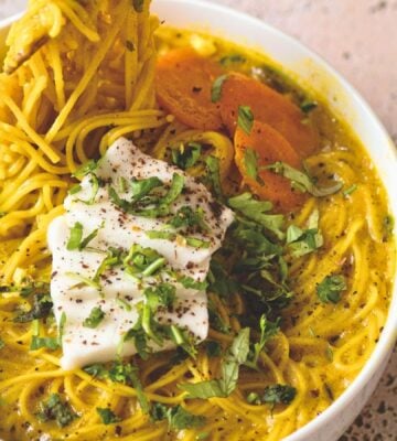 a bowl of vegan creamy coconut curry ramen with carrot, soft tofu, lime, and herbs for cozy lunch recipes for fall