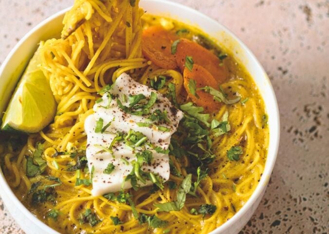 a bowl of vegan creamy coconut curry ramen with carrot, soft tofu, lime, and herbs for cozy lunch recipes for fall