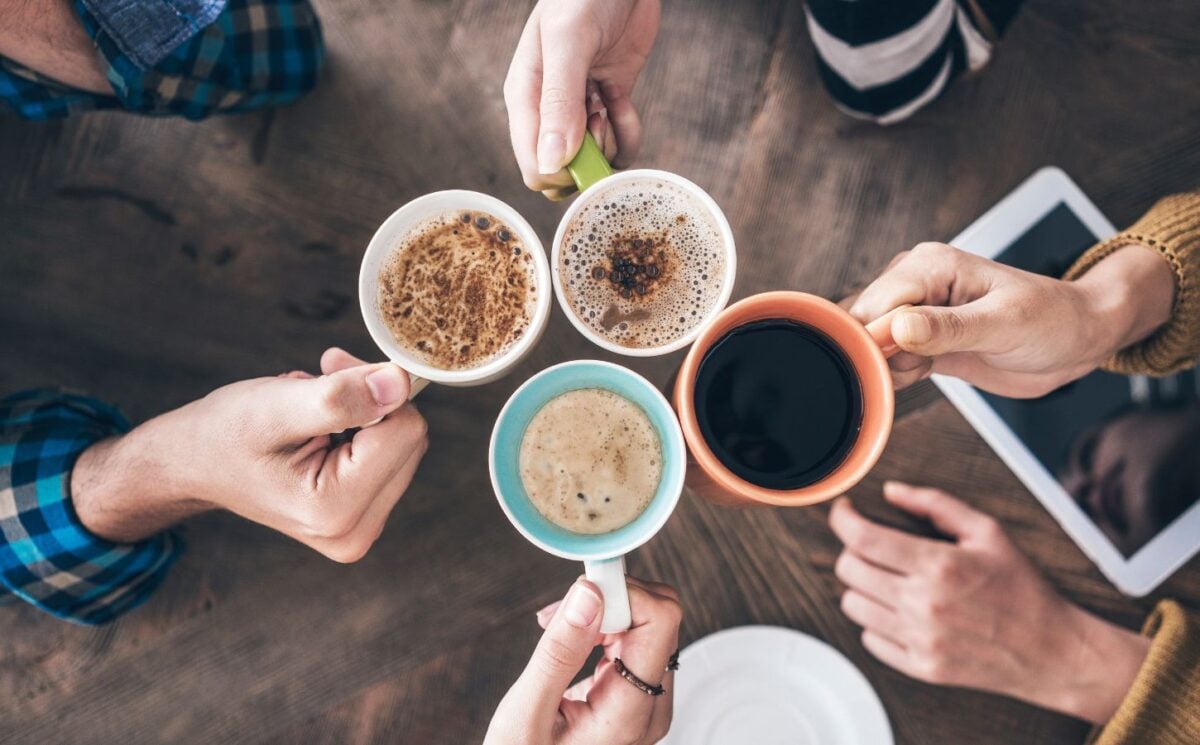 four people holding four cups of coffee for the topic of coffee's health effects