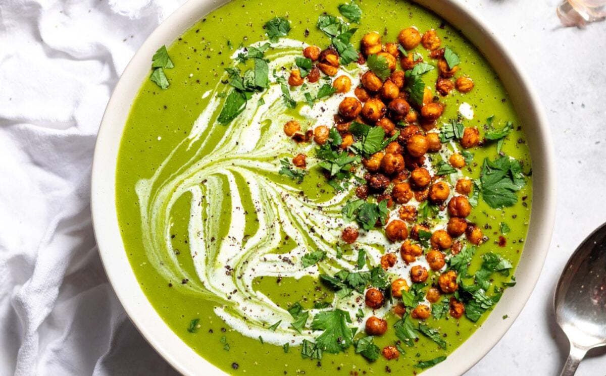 a bowl of pea and kale soup topped with vegan cream and roasted chickpeas for vegan soup recipes