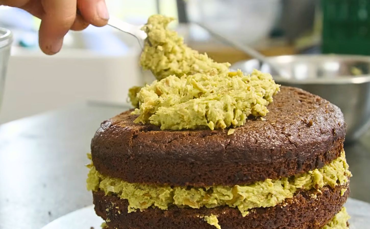 a freshly baked vegan Dubai chocolate cake with alternating layers of pistachio icing and vegan cake