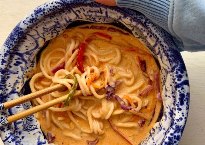one-pan ramen with bell pepper, carrot, ginger, garlic, and red cabbage in a coconut milk broth