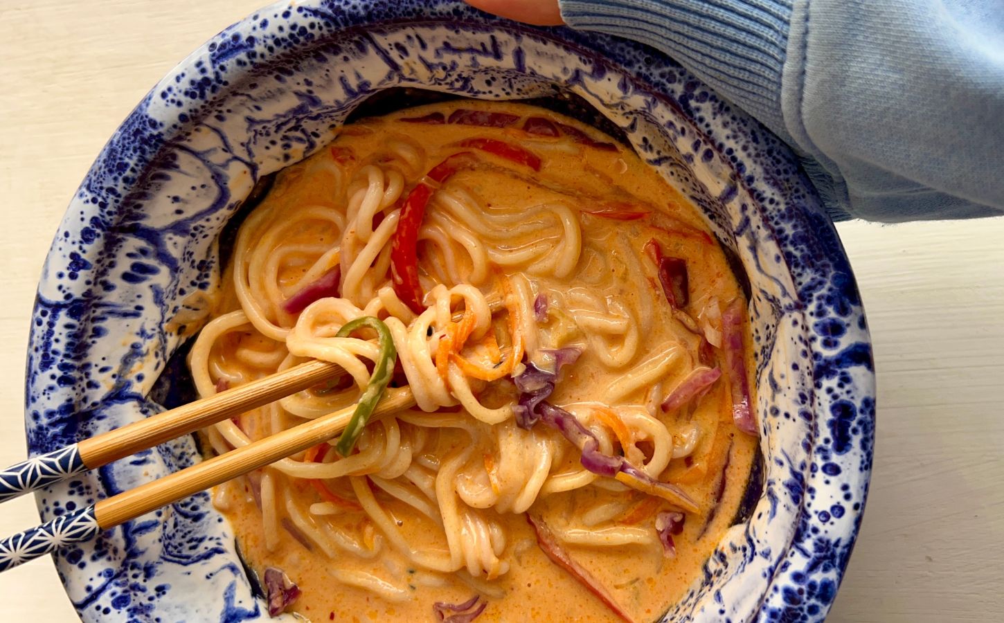 one-pan ramen with bell pepper, carrot, ginger, garlic, and red cabbage in a coconut milk broth