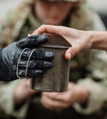 Photo shows three soldiers sitting together and sharing food and drink