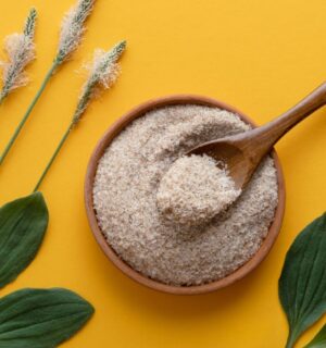 a photo of psyllium husk powder against a yellow background with psyllium plants