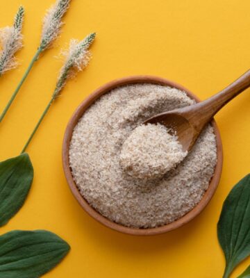 a photo of psyllium husk powder against a yellow background with psyllium plants