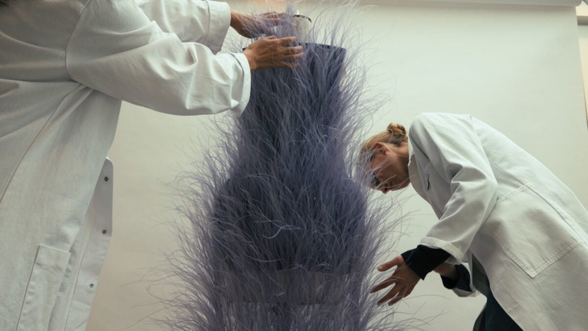 Photo shows two people working on one of the Stella McCartney outfits featuring vegan feathers