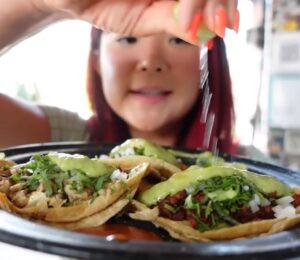Rose Lee holds a plate of vegan tacos and pours lemon over them while exploring Mexico City’s plant-based scene