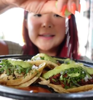 Rose Lee holds a plate of vegan tacos and pours lemon over them while exploring Mexico City’s plant-based scene