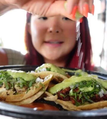 Rose Lee holds a plate of vegan tacos and pours lemon over them while exploring Mexico City’s plant-based scene